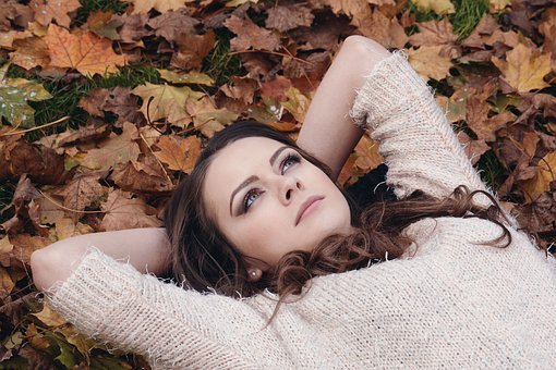 Femme allongée et bras croisés dans les feuilles
